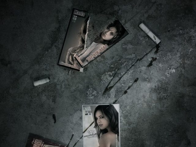 A photograph of two escort cards with splattered ketchup on a concrete sidewalk.