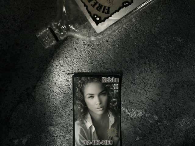 A photograph of an escort card, next to a bottle of Fireball on a sidewalk.