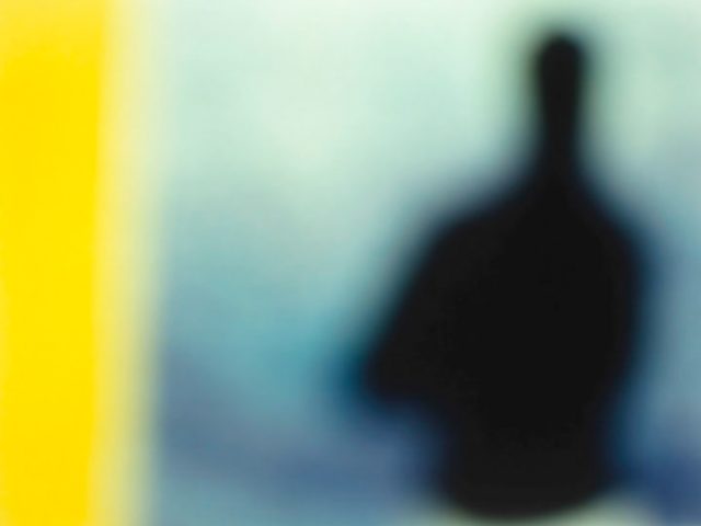 A soft focus image of a dark silhouette of a person against a blue backdrop, with a yellow band down the left side of the image.