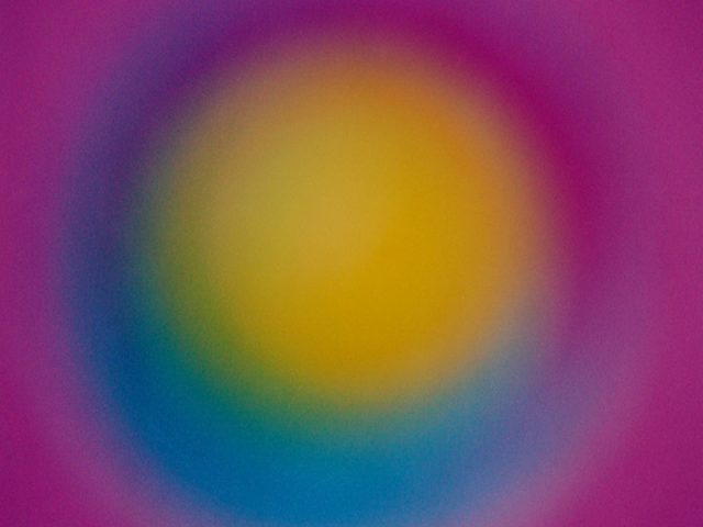 A colorful glowing orb of yellow with a blue perimeter and a purple background.