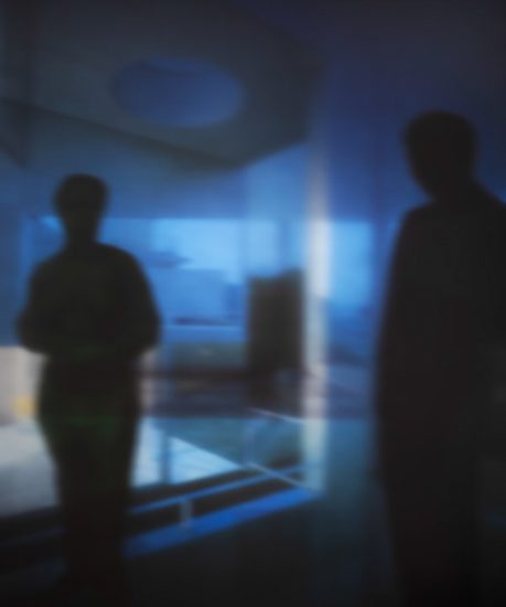 A soft focus image of two figures in blue surroundings.