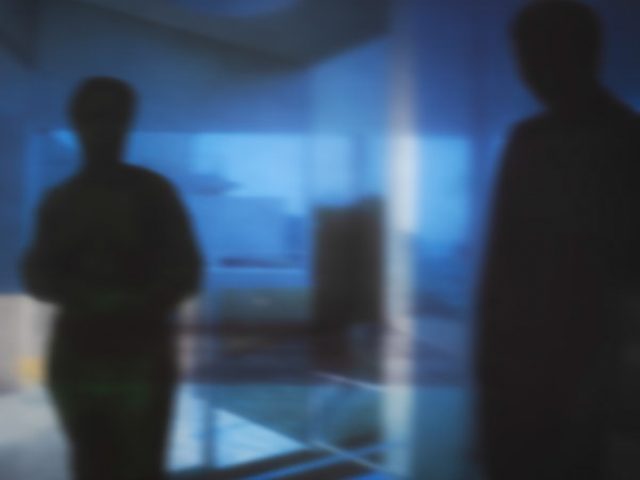A soft focus image of two figures in blue surroundings.