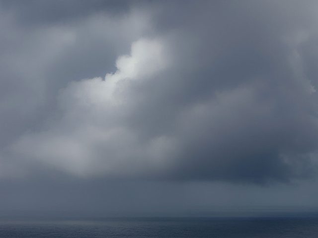 A photograph of a body of water with reflected light on the surface and a horizon line.