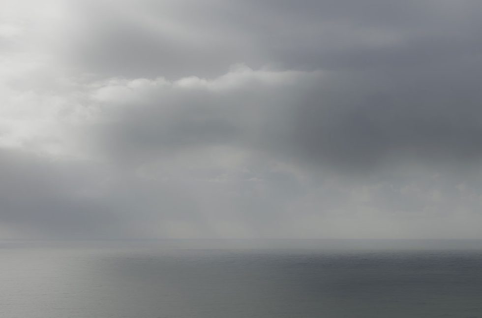 A photograph of a body of water with reflected light on the surface and a horizon line.