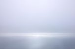 A photograph of a body of water with reflected light on the surface and a horizon line.
