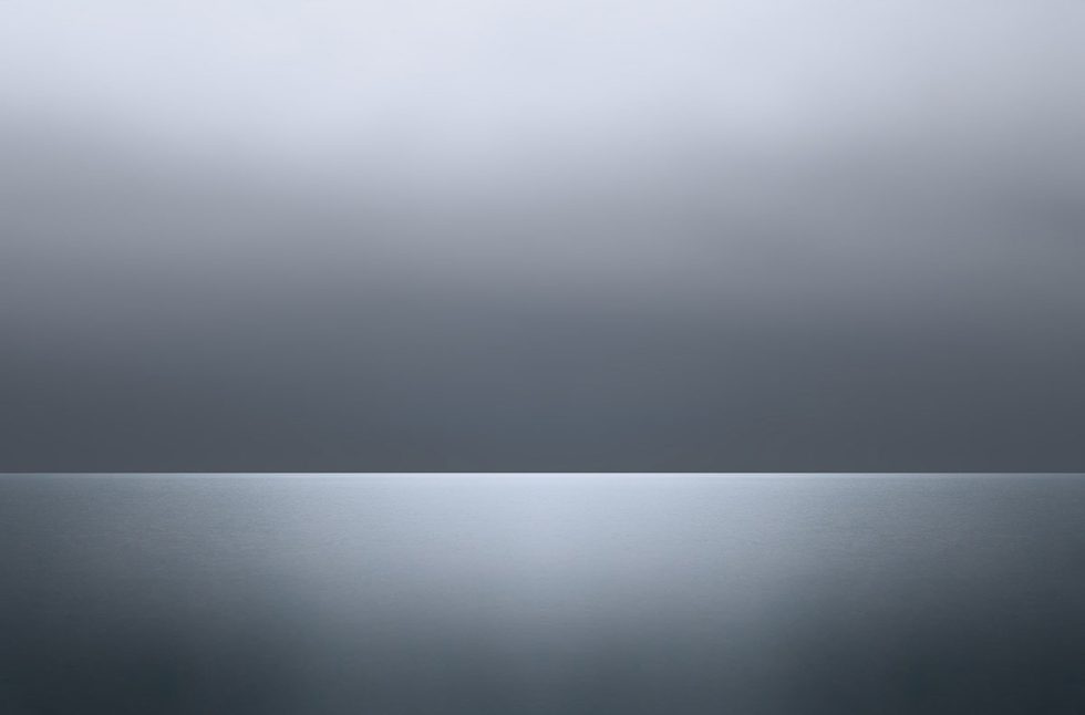 A photograph of a body of water with reflected light on the surface and a horizon line.