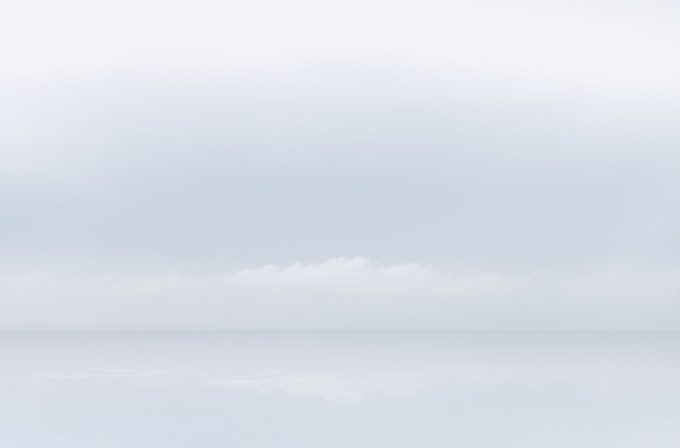 A photograph of a body of water with reflected light on the surface and a horizon line.