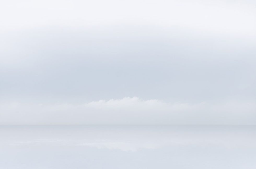 A photograph of a body of water with reflected light on the surface and a horizon line.