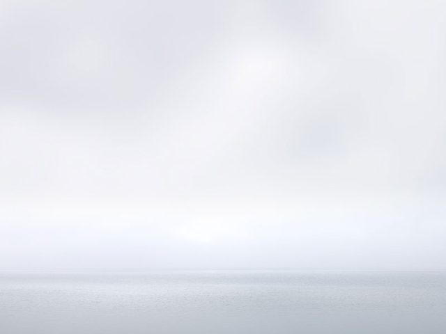 A photograph of a body of water with reflected light on the surface and a horizon line.