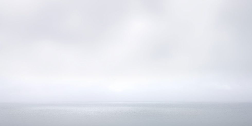 A photograph of a body of water with reflected light on the surface and a horizon line.