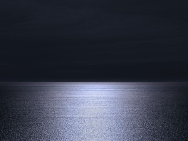 A photograph of a body of water with reflected light on the surface and a horizon line.