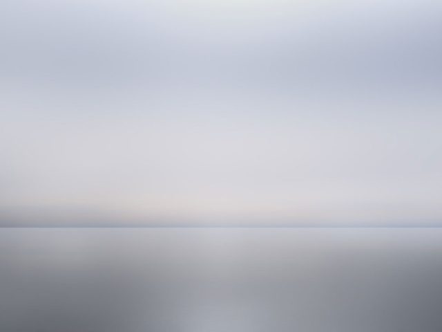 A photograph of as body of water with reflected light on the surface and a horizon line.