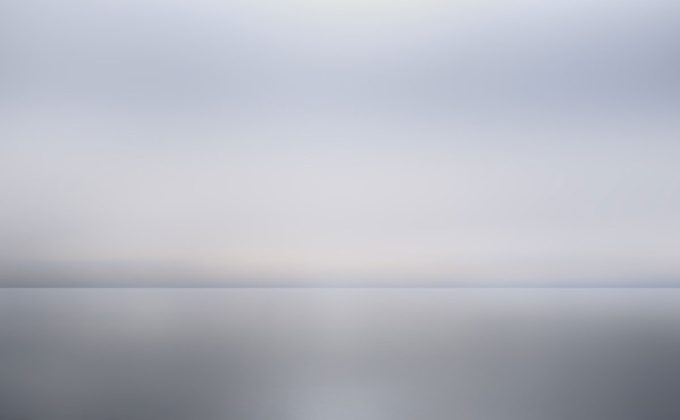 A photograph of as body of water with reflected light on the surface and a horizon line.