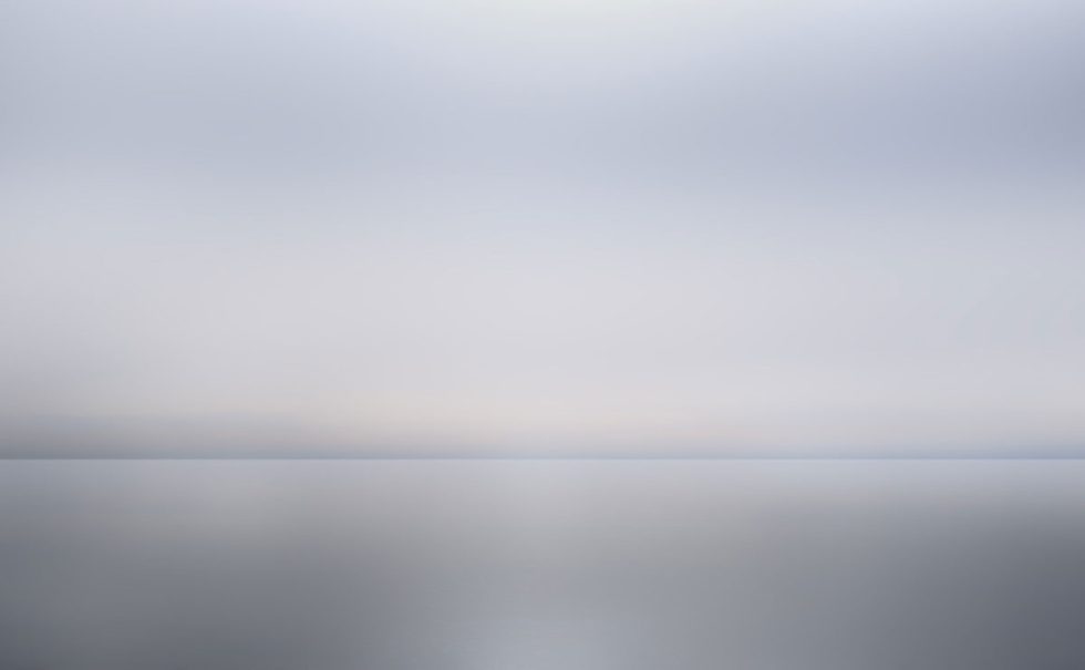 A photograph of as body of water with reflected light on the surface and a horizon line.