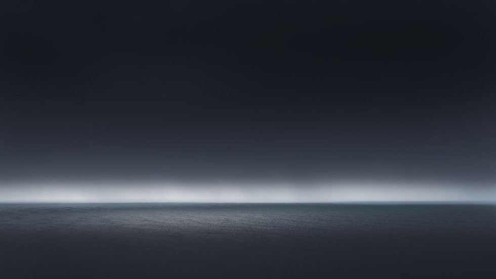 A photograph of a body of water with reflected light on the surface and a horizon line.