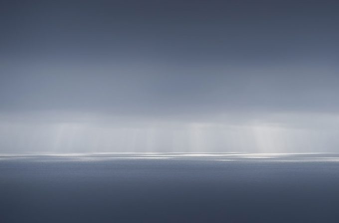 A photograph of a body of water with reflected light on the surface and a horizon line.