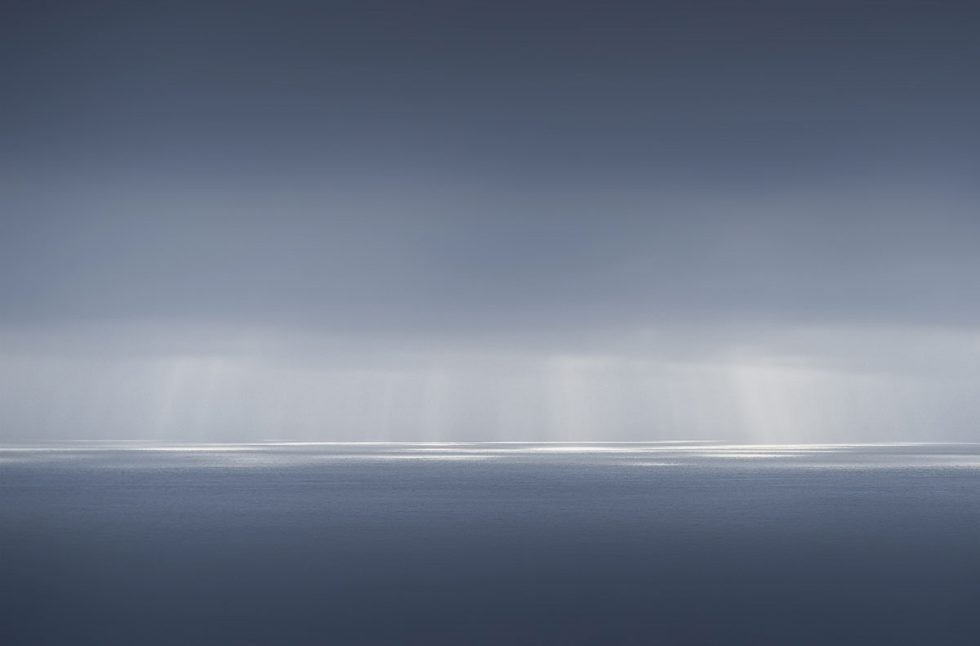 A photograph of a body of water with reflected light on the surface and a horizon line.
