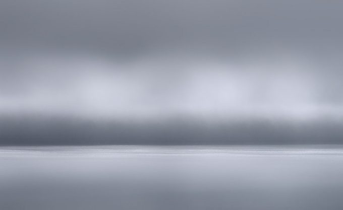 A photograph of a body of water with reflected light on the surface and a horizon line.