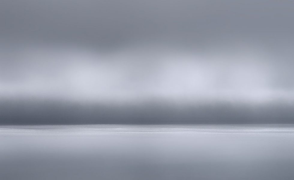 A photograph of a body of water with reflected light on the surface and a horizon line.