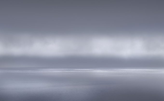 A photograph of a body of water with reflected light on the surface and a horizon line.