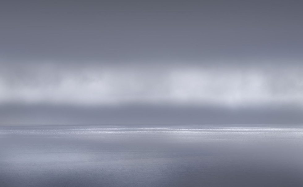 A photograph of a body of water with reflected light on the surface and a horizon line.