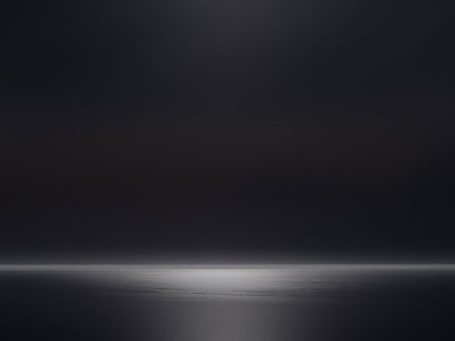 A photograph of a body of water with reflected light on the surface and a horizon line.