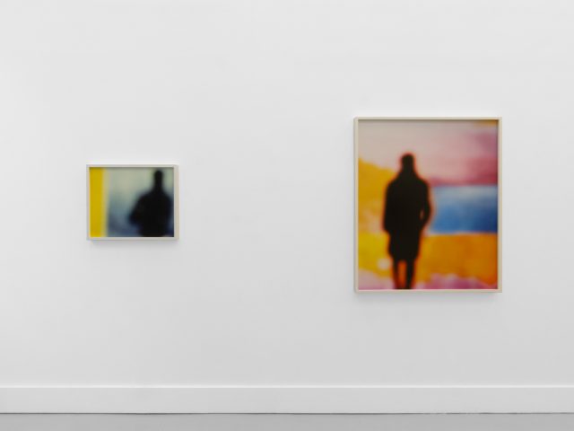 A photograph of an installation of colorful abstract works on a white gallery wall.