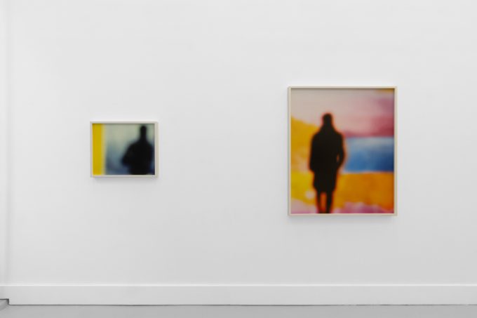 A photograph of an installation of colorful abstract works on a white gallery wall.