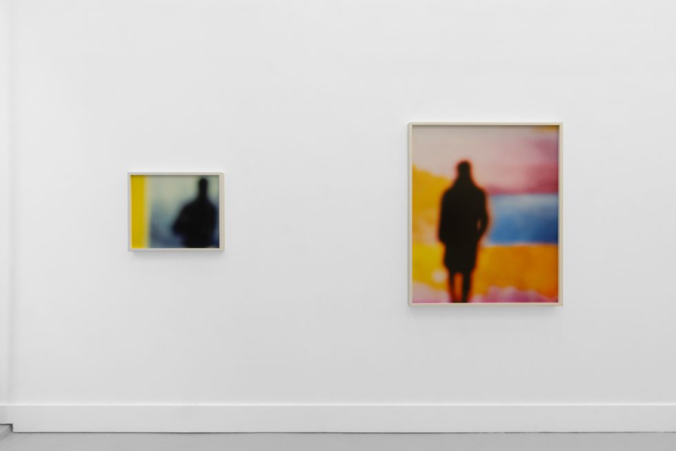 A photograph of an installation of colorful abstract works on a white gallery wall.