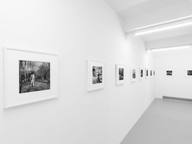 A photograph of black and white photographs in simple white frames on white gallery walls.