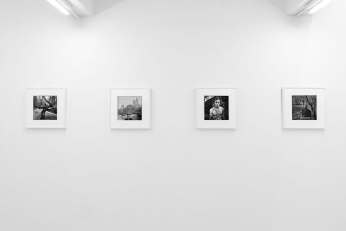 A photograph of black and white photographs in simple white frames on white gallery walls.