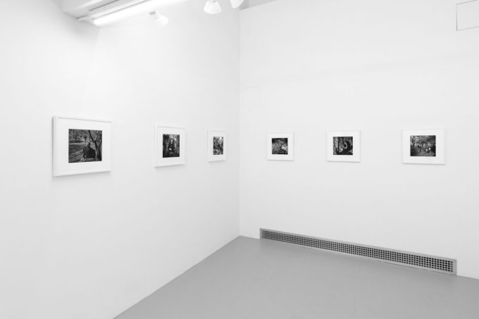A photograph of black and white photographs in simple white frames on white gallery walls.