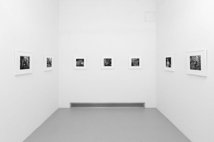 A photograph of black and white photographs in simple white frames on white gallery walls.