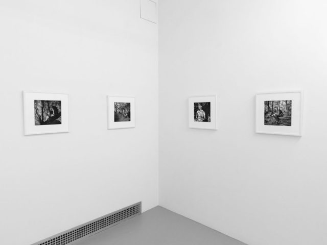 A photograph of black and white photographs in simple white frames on white gallery walls.