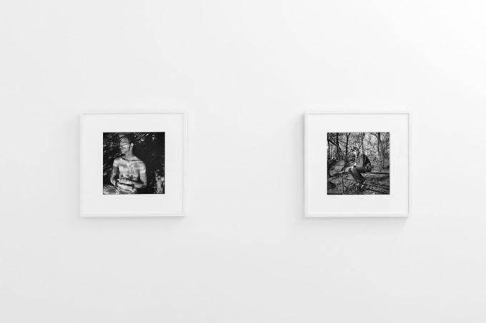 A photograph of black and white photographs in simple white frames on white gallery walls.