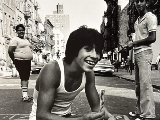 A black and white photograph of a boy with a boombox.