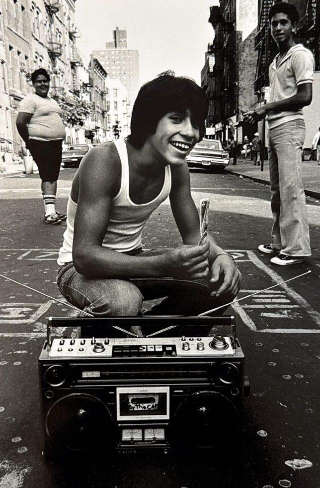 A black and white photograph of a boy with a boombox.