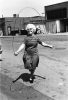 A black-and-white photograph of an older woman jumping rope on the street.
