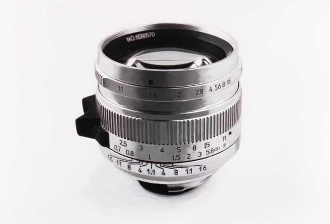 A black and white drawing of a silver camera lens on a white background.
