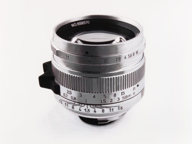 A black and white drawing of a silver camera lens on a white background.