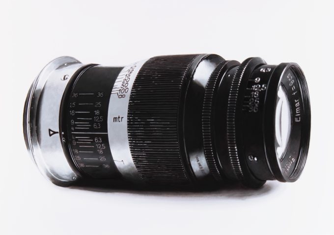 A black and white drawing of a camera lens on a white still life backdrop.