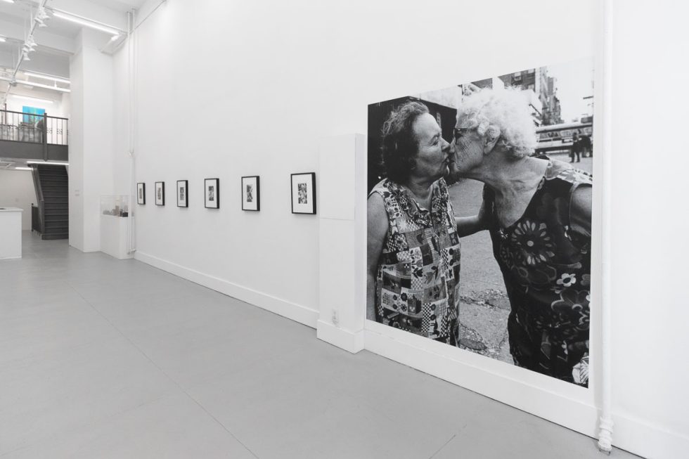 A photograph of a white-walled art gallery with black and white photographs with black frames on view.