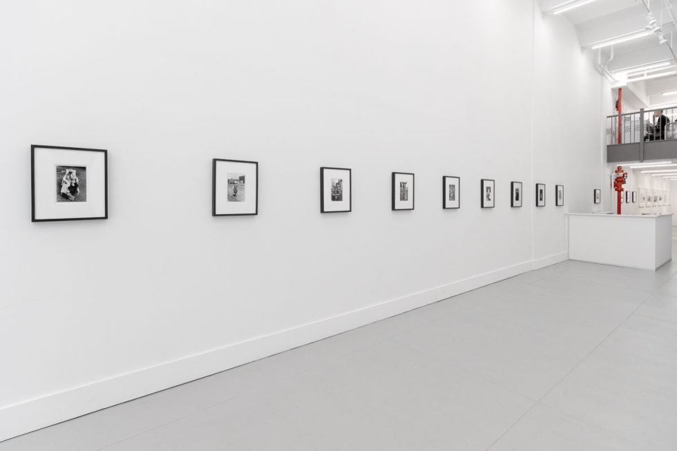 A photograph of a white-walled art gallery with black and white photographs with black frames on view.
