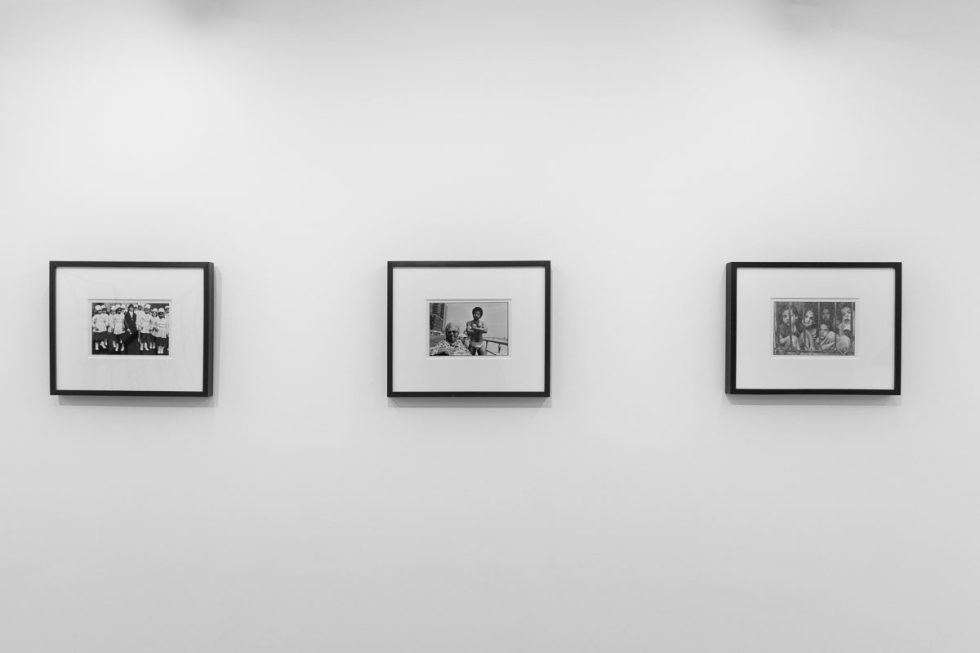 A photograph of a white-walled art gallery with black and white photographs with black frames on view.