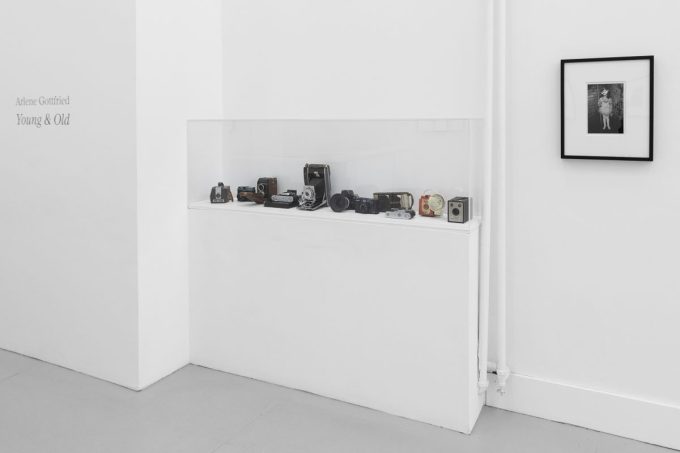 A photograph of a white-walled art gallery with black and white photographs with black frames on view.