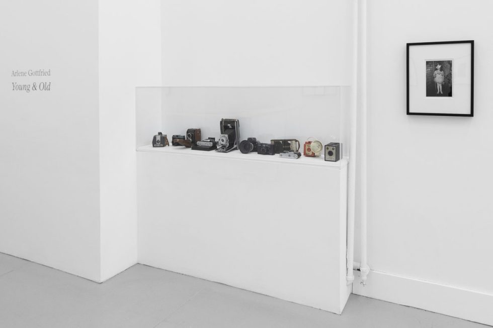 A photograph of a white-walled art gallery with black and white photographs with black frames on view.