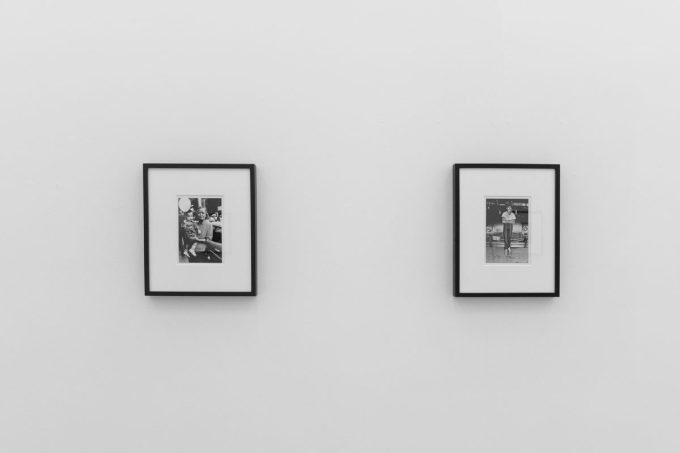 A photograph of a white-walled art gallery with black and white photographs with black frames on view.