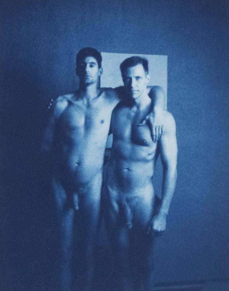 A cyanotype photograph of two nude men standing with their arms around each other's shoulders.