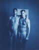A cyanotype photograph of two nude men standing with their arms around each other's shoulders.