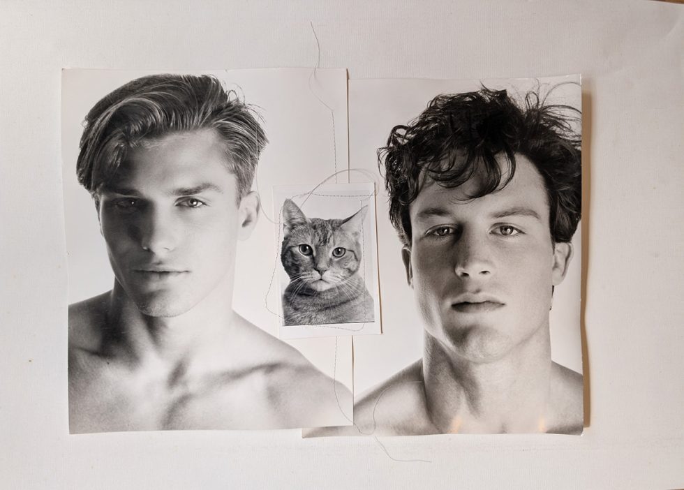 A black and white photograph of two handsome young men with a little kitty.